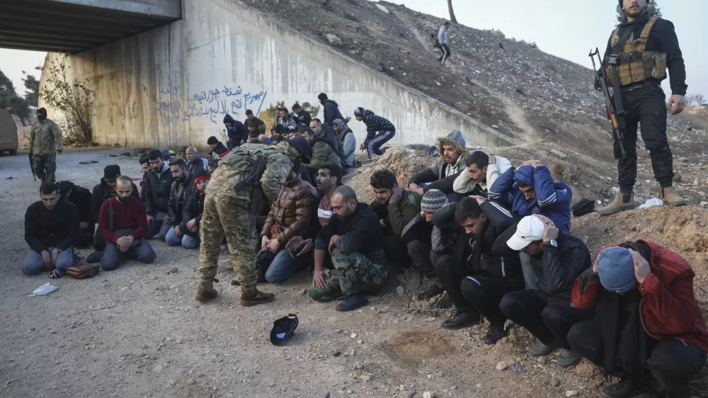Government soldiers and allies sit on the floor as they are taken into custody by opposition fighters on the road between Homs and Damascus, near Homs, Syria, on Sunday, Dec. 8, 2024. (AP Photo/Ghaith Alsayed)