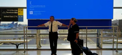 United Airlines employees wait by a departures monitor displaying a blue error screen, also known as the "Blue Screen of Death" inside Terminal C in Newark International Airport, after United Airlines and other airlines grounded flights due to a worldwide tech outage caused by an update to CrowdStrike's "Falcon Sensor" software which crashed Microsoft Windows systems, in Newark, New Jersey, U.S., July 19, 2024. REUTERS/Bing Guan   TPX IMAGES OF THE DAY