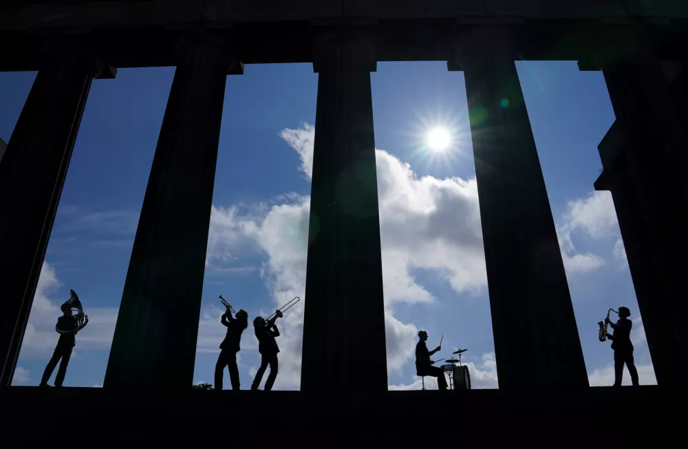 08 July 2021, United Kingdom, Edinburgh: Members of the band Brass Gumbo, Charles Dearness (Trumpet), Tom Pickles (Saxophone), Ross Lothian (Trombone) Rory Clark (Sousaphone) and Jamie Graham (Drums), play brass instruments in between the columns of the National Monument on Calton Hill in Edinburgh during a photocall for the Edinburgh Jazz and Blues Festival 2021. Photo: Andrew Milligan/PA Wire/dpa