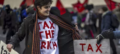Activist Marlene Engelhorn holds banners during a protest at the Meeting of World Economic Forum in Davos, Switzerland, Thursday, Jan. 23, 2025. (Michael Buholzer/Keystone via AP)