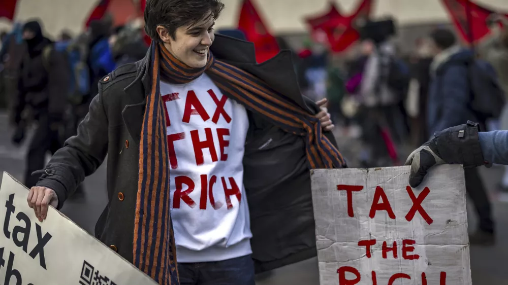 Activist Marlene Engelhorn holds banners during a protest at the Meeting of World Economic Forum in Davos, Switzerland, Thursday, Jan. 23, 2025. (Michael Buholzer/Keystone via AP)