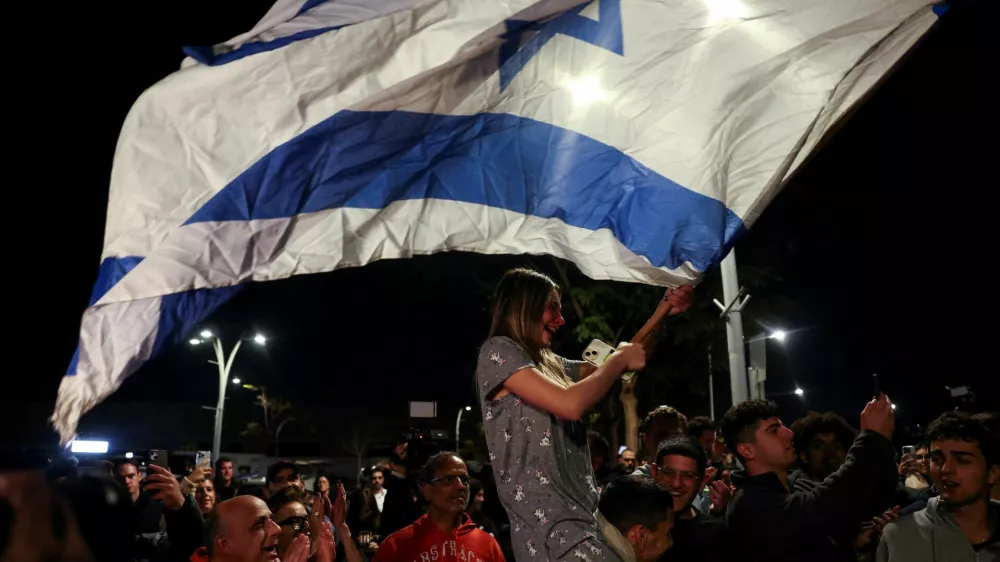 FILE PHOTO: A woman waves an Israeli flag, as people gather on the day of the arrival of Romi Gonen, Doron Steinbrecher and Emily Damari, three former female hostages who have been held in Gaza since the deadly October 7 2023 attack, following their release as part of a ceasefire deal in Gaza between Hamas and Israel, at Sheba Medical Center in Ramat Gan, Israel January 19, 2025. REUTERS/Ronen Zvulun/File Photo