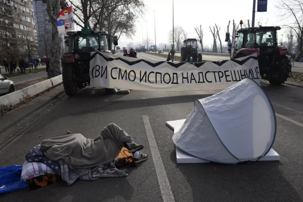 A man sleeps on the road during an ongoing protest over the collapse of a concrete canopy that killed 15 people more than two months ago, in Novi Sad, Serbia, Sunday, Feb. 2, 2025. (AP Photo/Darko Vojinovic)