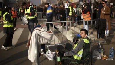 A student speaks at the loudspeaker to pedestrians during the blockage of the Bridge of Freedom and protest over the collapse of a concrete canopy killed 15 people more than two months ago, in Novi Sad, Serbia, Sunday, Feb. 2, 2025. (AP Photo/Armin Durgut)