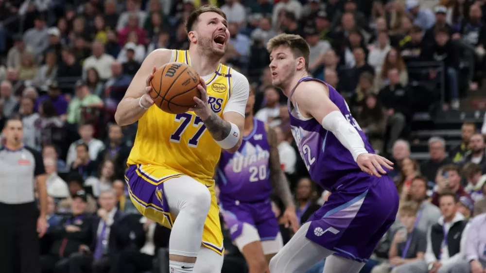 Feb 12, 2025; Salt Lake City, Utah, USA; Los Angeles Lakers guard Luka Doncic (77) is fouled by Utah Jazz forward Kyle Filipowski (22) during the second quarter at Delta Center. Mandatory Credit: Chris Nicoll-Imagn Images