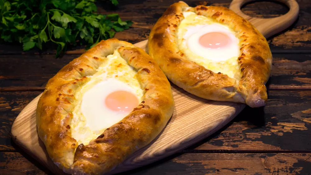 Georgian cuisine Adjarian khachapuri on a brown wooden background, caucasian cuisine, republic of Georgia / Foto: Andrey Lebedev