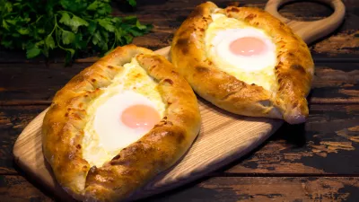 Georgian cuisine Adjarian khachapuri on a brown wooden background, caucasian cuisine, republic of Georgia / Foto: Andrey Lebedev