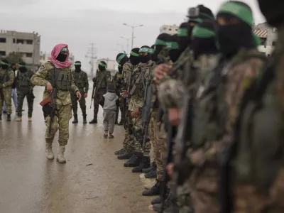 CORRECTS THE NAME OF THE CITY AS NUSEIRAT - Hamas fighters stand in formation ahead of the planned release of Israeli hostages set to be handed over to the Red Cross in Nuseirat, Gaza Strip, Saturday, Feb. 22, 2025. (AP Photo/Abdel Kareem Hana)