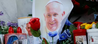 A photo of Pope Francis is placed next to candles and flowers at the base of the statue of the late Pope John Paul II outside the Gemelli Hospital where Pope Francis is admitted for treatment, in Rome, Italy, February 23, 2025. REUTERS/Ciro De Luca