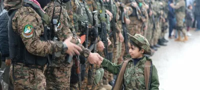 FILE PHOTO: A Palestinian Hamas militant shakes hands with a child as they stand guard as people gather on the day of the handover of hostages, including four held in Gaza since the deadly October 7 2023 attack, to members of the International Committee of the Red Cross (ICRC) as part of a ceasefire and a hostages-prisoners swap deal between Hamas and Israel, in Rafah in the southern Gaza Strip, February 22, 2025. REUTERS/Ramadan Abed/File Photo