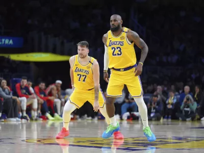 Los Angeles Lakers' LeBron James (23) and Luka Doncic (77) watch action during the second half of an NBA basketball game against the New Orleans Pelicans Tuesday, March 4, 2025, in Los Angeles. (AP Photo/Jae C. Hong)