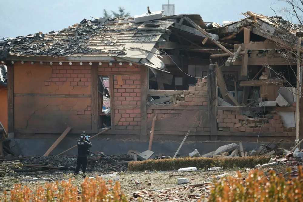 A forensic officer takes photographs of a building damaged after South Korea's Air Force said that Mk82 bombs fell from a KF-16 jet outside the shooting range during joint live-fire exercises near the demilitarized zone separating two Koreas in Pocheon, South Korea, March 6, 2025. REUTERS/Kim Hong-Ji   TPX IMAGES OF THE DAY