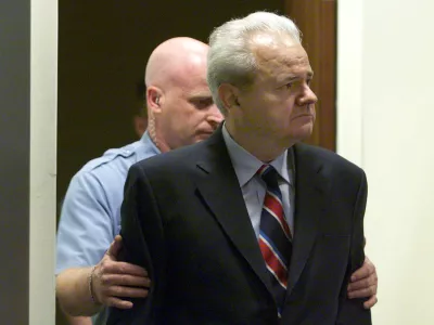*** FILE *** Former Yugoslav President Slobodan Milosevic, right, with court security guard behind him, enters the U.N. war crimes tribunal in The Hague, Tuesday July 3, 2001. Milosevic has died in the UN war crimes tribunal's detention center in the Hague Saturday March 11, 2006 according to Belgrade's B-92 and Serbia's state radio. He was 65.(AP Photo/pool)