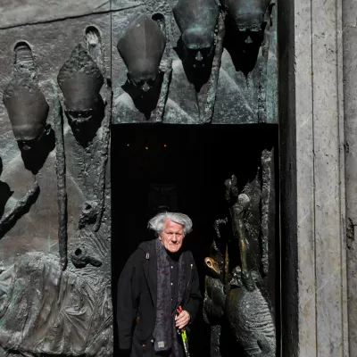 Dvainsedemdesetletni kipar Mirsad Begić pri stranskih vratih v ljubljansko stolnico, ki veljajo za tisto njegovo stvaritev, na katero je najbolj ponosen. Foto: Bojan Velikonja