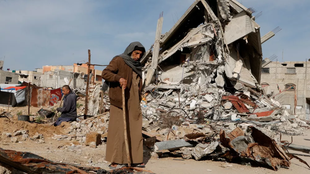 FILE PHOTO: A Palestinian man walks near rubble of houses destroyed during the Israeli offensive, in Rafah, in the southern Gaza Strip, March 13, 2025. REUTERS/Hatem Khaled/File Photo