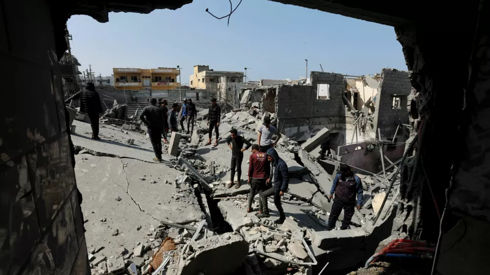 Palestinians inspect the site of an Israeli strike on a residential building, in Deir Al-Balah in the central Gaza Strip March 18, 2025. REUTERS/Ramadan Abed