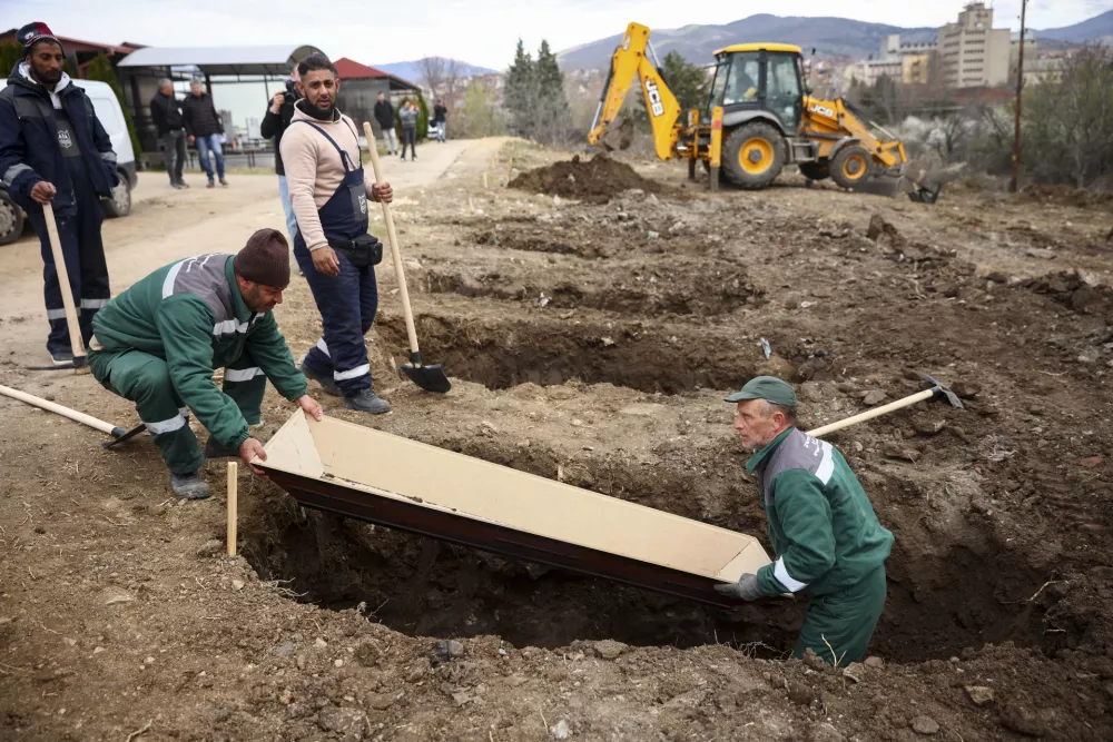 Municipal workers use an empty coffin to measure the graves they are digging for the victims of a massive nightclub fire, in the town of Kocani, North Macedonia, Tuesday, March 18, 2025. (AP Photo/Armin Durgut)