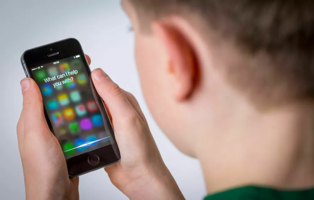 HN3525 A teenage boy using Siri on an iPhone