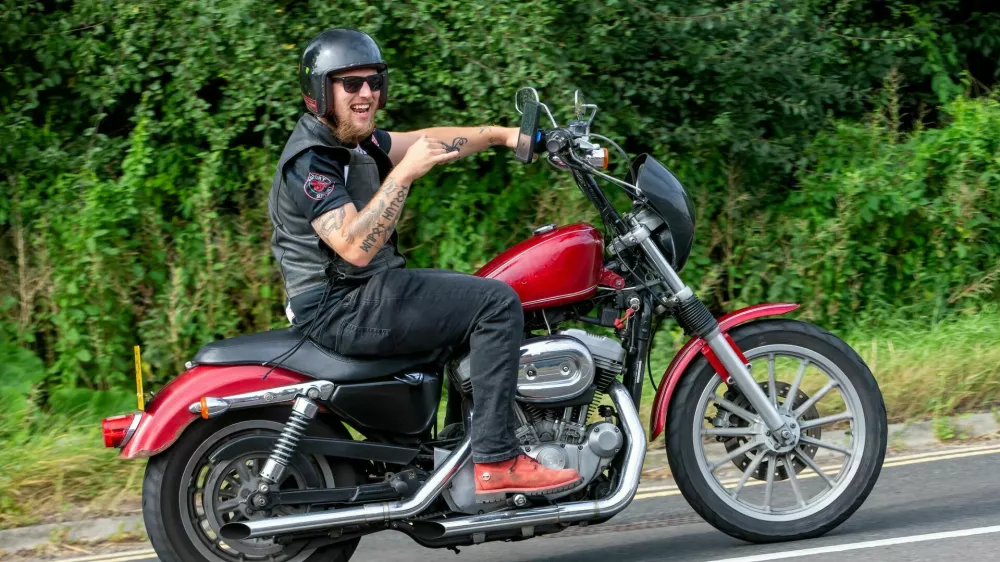 Potterspury,Northants,UK - Aug 11th 2024: Man riding a red 2005 Harley Davidson XL883 motorcycle travelling on a British road / Foto: Sue Thatcher