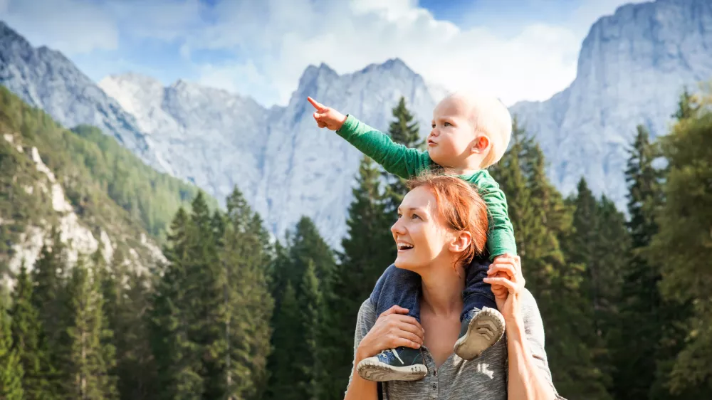 Srečna mamica z otročičkom med lepimi gorami. / Foto: Istock