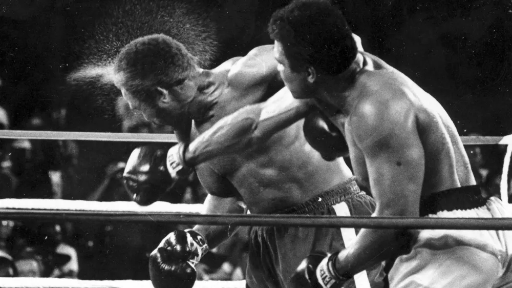 FILE - Perspiration flies from the head of George Foreman as he takes a right from challenger Muhammad Ali in the seventh round in the match dubbed Rumble in the Jungle in Kinshasa, Zaire, Oct. 30, 1974. (AP Photo/Ed Kolenovsky, File)