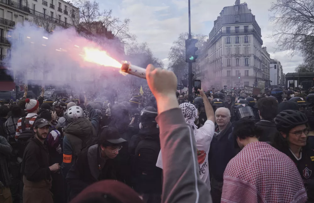 A protestor holds a smoke bomb during a march as part of the international day against racism and fascism, in Paris, Saturday, March 22, 2025. (AP Photo/Thibault Camus)