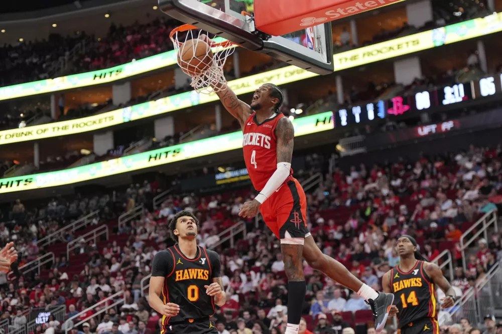 Houston Rockets' Jalen Green (4) dunks the ball as Atlanta Hawks' Dominick Barlow (0) watches during the second half of an NBA basketball game Tuesday, March 25, 2025, in Houston. (AP Photo/David J. Phillip)