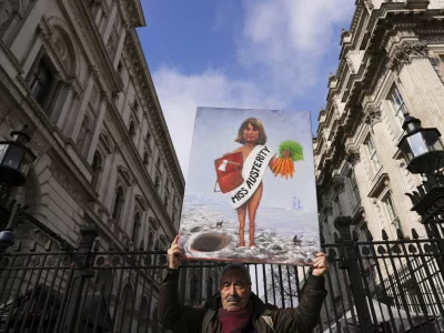 Artist Kaya Mar holds a painting depicting Chancellor Rachel Reeves at the entrance gate to Downing Street in London, Wednesday, March 26, 2025. (AP Photo/Kirsty Wigglesworth)