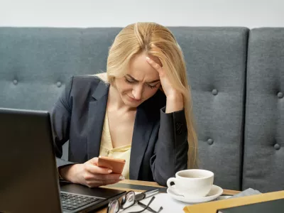 Dissatisfied surprised caucasian young woman look at smartphone screen in the home office. / Foto: Okskukuruza
