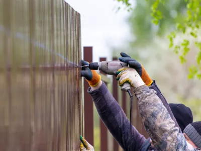 Workers install a metal profile fence. / Foto: Schankz