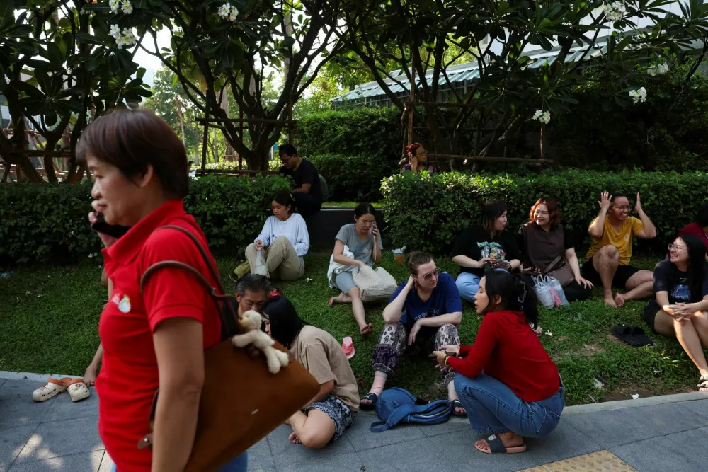 People sit next to a pavement while waiting after a strong earthquake struck central Myanmar on Friday, earthquake monitoring services said, which affected Bangkok as well with hundreds of people pouring out of buildings in the Thai capital in panic after the tremors, in Bangkok, Thailand, March 28, 2025. REUTERS/Chalinee Thirasupa