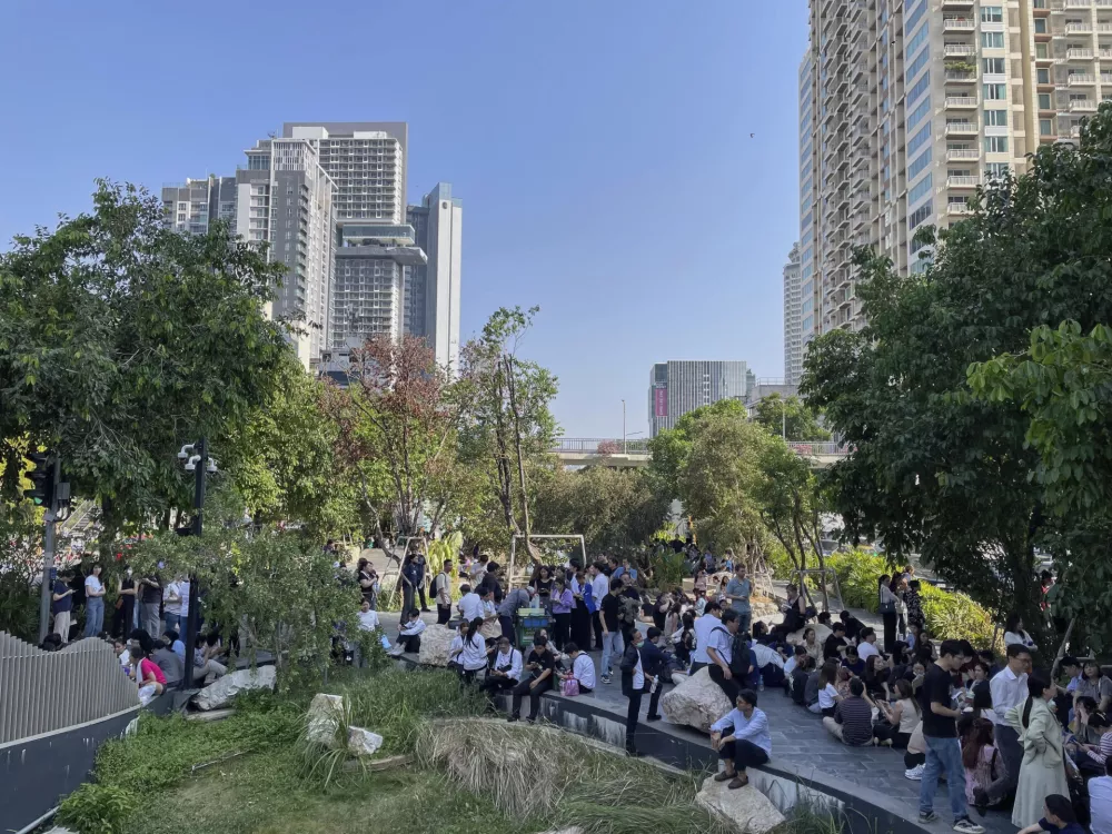 Office workers and residents who evacuated high-rise buildings after an earthquake wait in the shade along a canal in Bangkok, Friday, March 28, 2025. (AP Photo/Christie Hampton)
