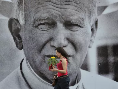 A Polish woman passes by a giant poster of the late Pope John Paul II in downtown Krakow, Poland, Thursday, April 28, 2011. An open-air photo exhibition in Krakow remembers Poland's most beloved and revered son, Pope John Paul II before his beatification ceremony in Rome on Sunday. (AP Photo/Bela Szandelszky)
