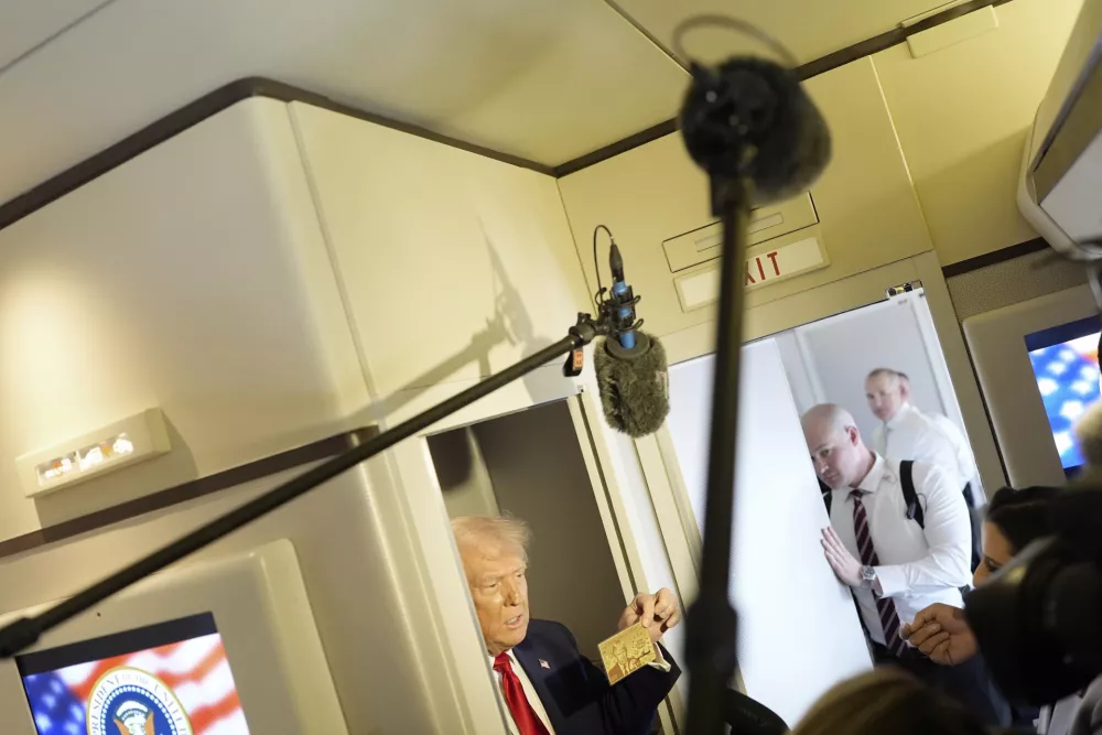 President Donald Trump holds up the $5 million gold card as he speaks to reporters while in flight on board Air Force One, en route to Miami, Thursday, April 3, 2025. (Pool via AP)