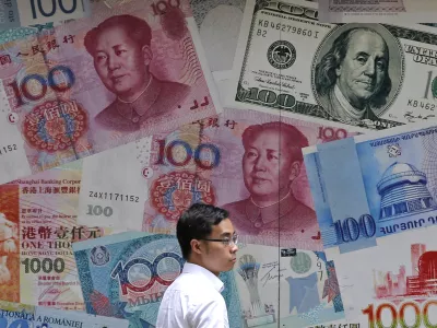 FILE - In this June 10, 2019, file photo, a man walks past a money exchange shop decorated with different banknotes at Central, a business district of Hong Kong. China's yuan fell Friday, Aug. 2, 2019, to its lowest level of the year against the dollar following U.S. President Donald Trump's threat of new tariffs on Chinese goods, coming close to breaking the politically sensitive level of seven to the U.S. currency. (AP Photo/Kin Cheung, File)