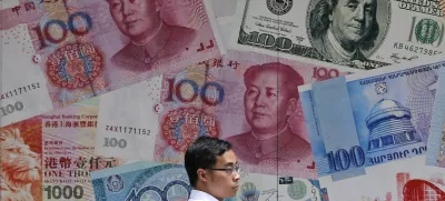 FILE - In this June 10, 2019, file photo, a man walks past a money exchange shop decorated with different banknotes at Central, a business district of Hong Kong. China's yuan fell Friday, Aug. 2, 2019, to its lowest level of the year against the dollar following U.S. President Donald Trump's threat of new tariffs on Chinese goods, coming close to breaking the politically sensitive level of seven to the U.S. currency. (AP Photo/Kin Cheung, File)
