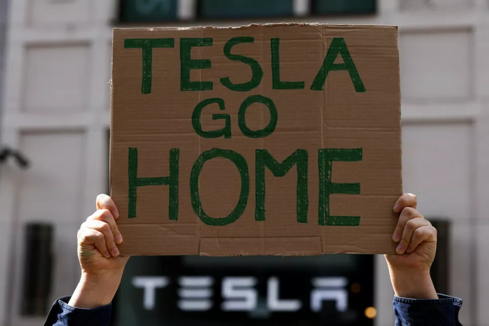 A person holds a placard during a protest outside a Tesla showroom at Mall of Berlin under the slogan "#TeslaTakedown" against Tesla and its CEO Elon Musk and against what organisers say is the destruction of democracy and the climate by the rich, in Berlin, Germany, April 5, 2025. REUTERS/Christian Mang