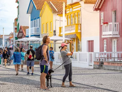 Tourists take photos of typical multicolored striped houses in Costa Nova, Aveiro, Portugal. COSTA NOVA, PORTUGAL - August 19, 2019.