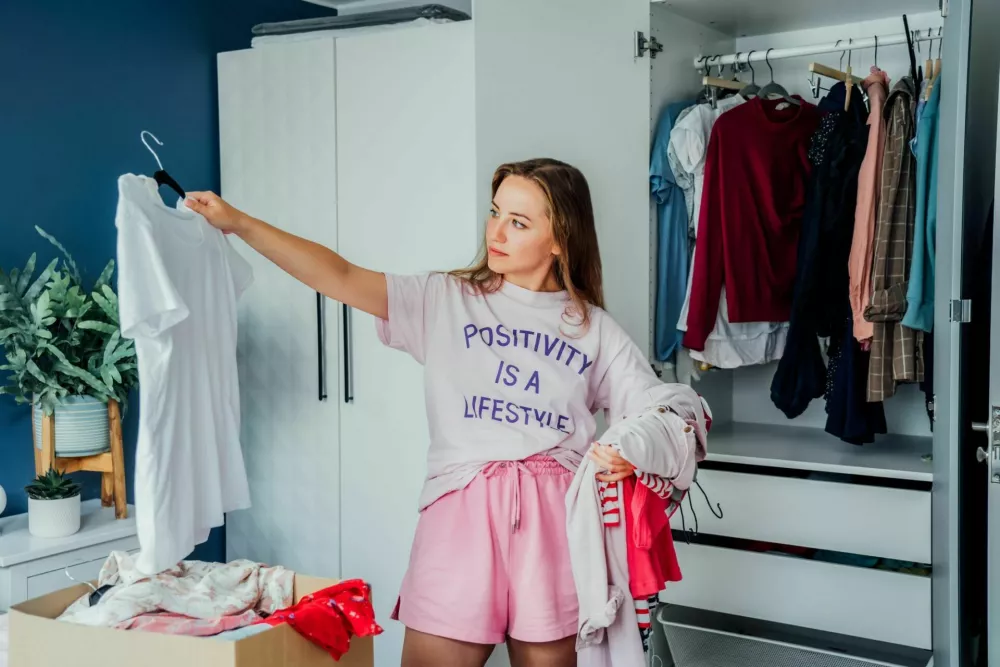 Woman selecting clothes from her wardrobe for donating to a Charity shop. Decluttering, Sorting clothes and Cleaning Up. Reuse, second-hand concept. Conscious consumer, sustainable lifestyle / Foto: Okrasyuk