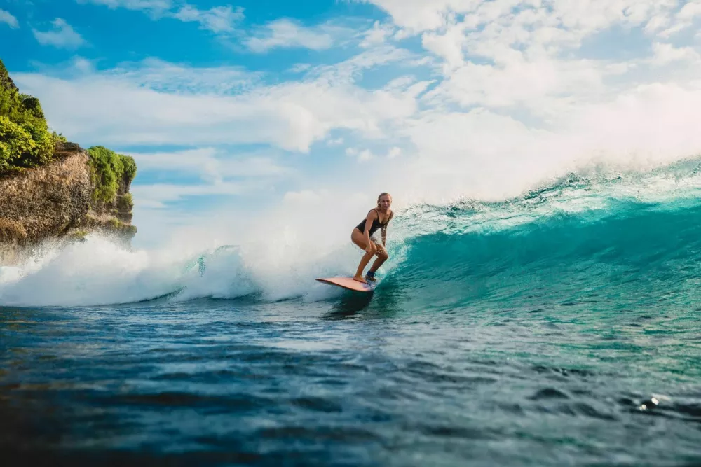 Surf girl on surfboard. Woman in ocean during surfing. Surfer and ocean wave / Foto: Nuture