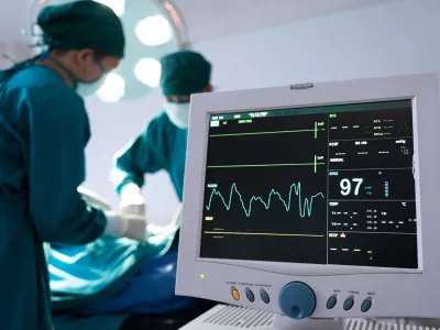 Selective at monitor and nurse using defibrillator to pump at chest of unconscious with low heart rate patient to save life while doing medical surgery inside of operating room. Emergency CPR. / Foto: Stock Photo And Footage