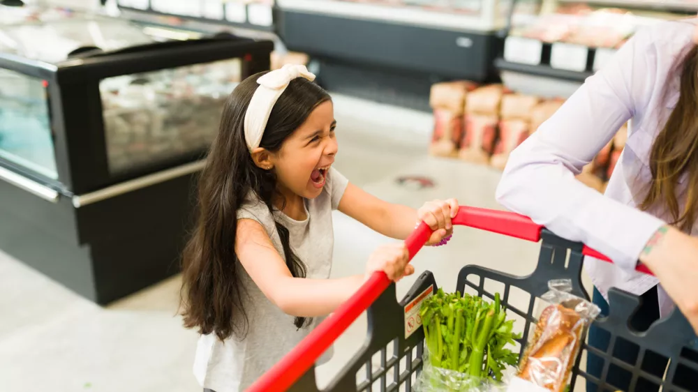 Angry little kid screaming and throwing a tantrum while grocery shopping with her mom at the supermarket because she won't buy her candy / Foto: Antonio_diaz