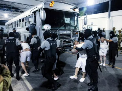 In this photo provided by El Salvador's presidential press office guards transfer deportees from the U.S to the Terrorism Confinement Center in Tecoluca, El Salvador, Monday, March 31, 2025. (El Salvador presidential press office via AP)