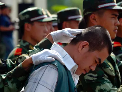 A Chinese paramilitary officer keeps the head of a drug dealer bowed during a public sentencing to mark International Day against Drug Abuse and Illicit Drug Trafficking in Hangzhou, eastern China's Zhejiang province, Monday, June 26, 2006. Chinese drug control officials said Thursday their yearlong war on drugs has severely squeezed heroin supplies from the Golden Triangle. Officials also announced the arrest of some 46,000 drug suspects and the seizure of some 6.9 tons of heroin last year. During the trial in Hangzhou, 20 drug dealers were sentenced today with three given the death penalty and executed soon after. (AP Photo) ** CHINA OUT **