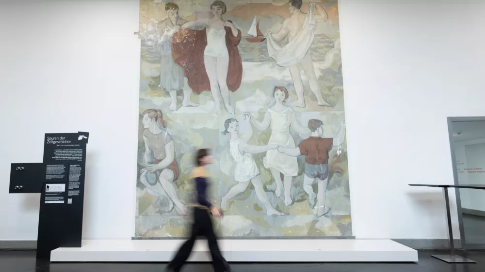 07 April 2025, Dresden: A woman walks in front of an early work by Gerhard Richter during a press conference at the Hygiene Museum (DHMD). The mural "Lebensfreude" in the museum's foyer was created in 1956 as Gerhard Richter's graduation work and was painted over in 1979. After a long restoration, the painting has been partially unveiled in Dresden for the first time in over 40 years. Photo: Sebastian Kahnert/dpa - ACHTUNG: Nur zur redaktionellen Verwendung im Zusammenhang mit der aktuellen Berichterstattung