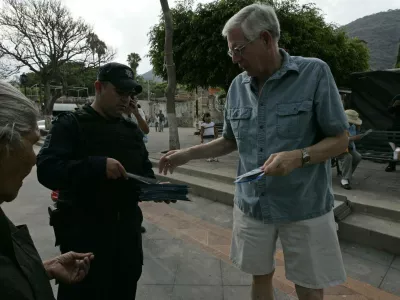 A policeman hands out a leaflet with security information to a foreign resident in the town of Ajijic, in the Mexican State of Jalisco, May 16, 2012. About 400 U.S. and Canadian citizens gathered on Wednesday to meet with officials of the municipal police to demand for more security. Ajijic, on the shore of Chapala lake, is one of the populations with the highest number of foreigners residing in Mexico and has been plagued by kidnappings and vendettas between rival groups of drug trafficking in the past months, local media reported. REUTERS/Alejandro Acosta (MEXICO - Tags: CIVIL UNREST SOCIETY CRIME LAW)