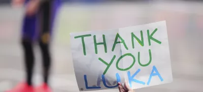 A fan holds up a sign thanking Los Angeles Lakers' Luka Doncic as he stands on the court at rear late in the second half of an NBA basketball game against the Dallas Mavericks in Dallas, Wednesday, April 9, 2025. (AP Photo/LM Otero)