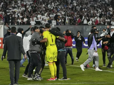 Goalkeeper Brayan Cortes of Chile's Colo Colo confronts fans who invaded the field during a Copa Libertadores Group E soccer match against Brazil's Fortaleza at the Monumental stadium in Santiago, Chile, Thursday, April 10, 2025. (AP Photo/Esteban Felix)