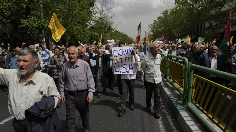 A demonstrator carries an anti-U.S. placard in an anti-Israeli rally after the Friday prayer in Tehran, Iran, Friday, April 11, 2025. (AP Photo/Vahid Salemi)