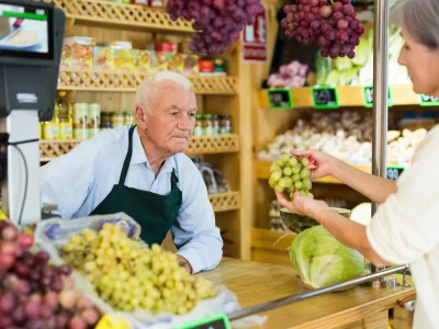 Woman asks the seller to weigh bunch of grapes on the scales / Foto: Jackf